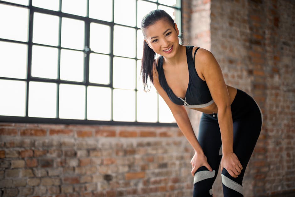 Happy woman in sportswear stretching on a yoga mat by a large window
